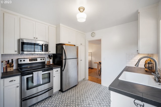 kitchen featuring tasteful backsplash, sink, white cabinets, and appliances with stainless steel finishes