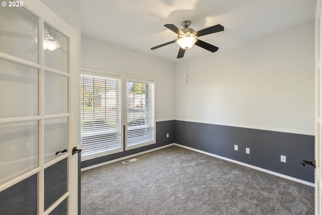 carpeted empty room with ceiling fan, visible vents, and baseboards