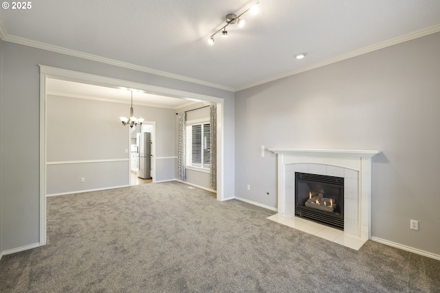 unfurnished living room with carpet, crown molding, a tiled fireplace, an inviting chandelier, and baseboards