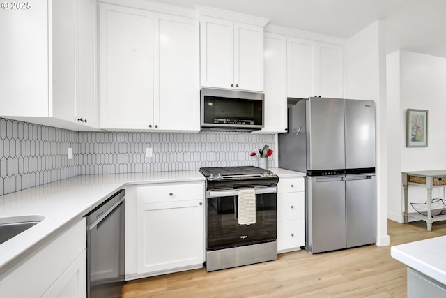kitchen featuring stainless steel appliances, light countertops, decorative backsplash, and white cabinets