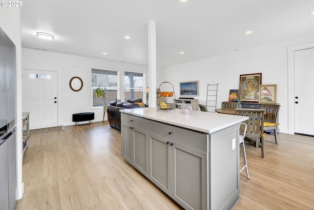 1723 Dotie Dr, Springfield, OR 97477 - kitchen with gray cabinetry, open floor plan, light wood-style flooring, light countertops, and a breakfast bar area