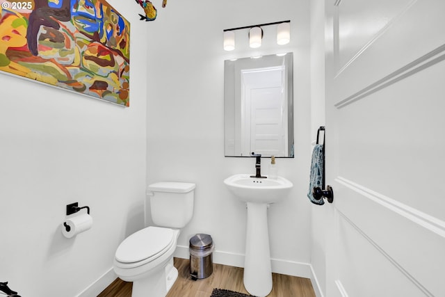 bathroom with toilet, baseboards, and wood finished floors
