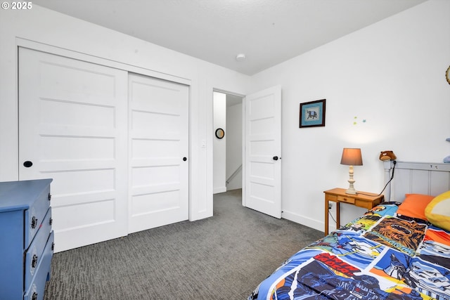 bedroom with dark colored carpet, a closet, and baseboards