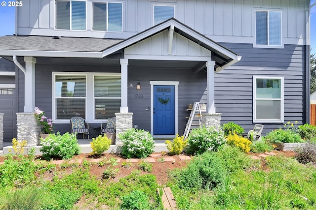 view of exterior entry with a porch, board and batten siding, and roof with shingles