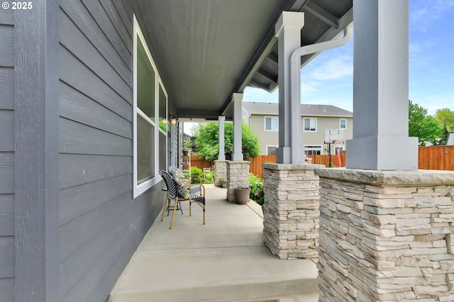view of patio / terrace featuring fence and a porch