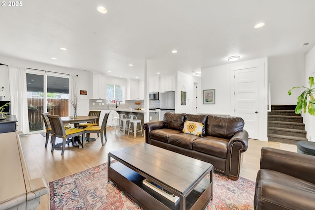 living area featuring stairway, light wood-style floors, and recessed lighting