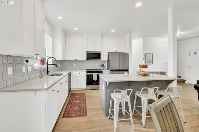 kitchen with a sink, stainless steel appliances, tasteful backsplash, a kitchen island, and a kitchen breakfast bar