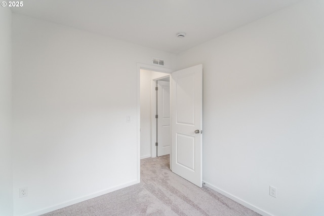 spare room with baseboards, visible vents, and light colored carpet