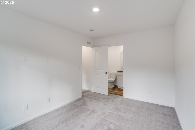 unfurnished bedroom with light colored carpet, visible vents, baseboards, recessed lighting, and ensuite bath
