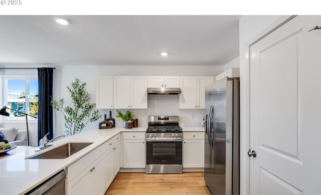 kitchen featuring white cabinetry, a sink, stainless steel appliances, light countertops, and under cabinet range hood