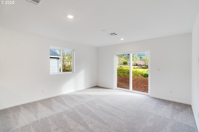 spare room featuring visible vents, light carpet, and plenty of natural light