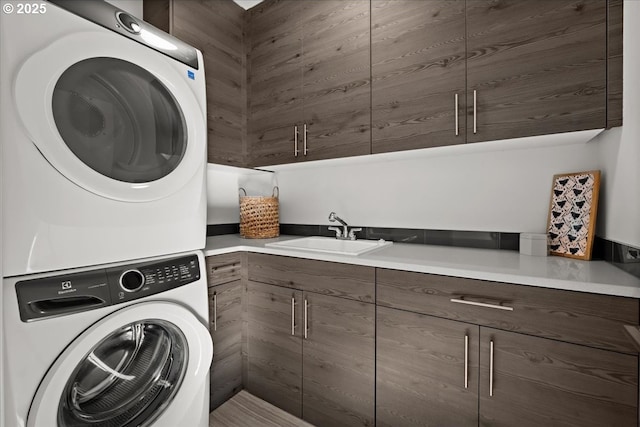 laundry room with a sink, cabinet space, and stacked washer / drying machine