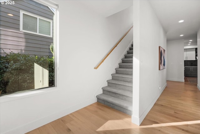 staircase with baseboards, wood finished floors, and recessed lighting