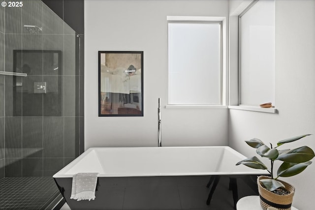 bathroom with a soaking tub and a tile shower