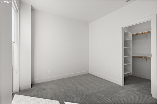 unfurnished bedroom with a spacious closet, a closet, carpet flooring, and baseboards