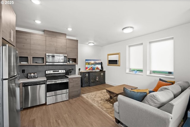 kitchen with modern cabinets, appliances with stainless steel finishes, open floor plan, light countertops, and light wood-type flooring