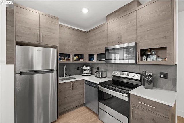 kitchen featuring stainless steel appliances, a sink, light countertops, decorative backsplash, and open shelves