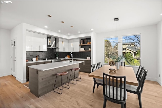 kitchen with white cabinets, wall chimney exhaust hood, modern cabinets, light wood-style floors, and open shelves