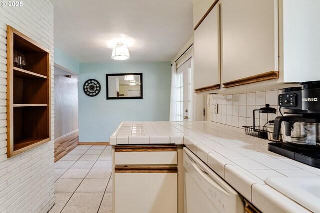 kitchen with stainless steel electric stove, brick wall, a kitchen breakfast bar, tile counters, and light tile patterned floors