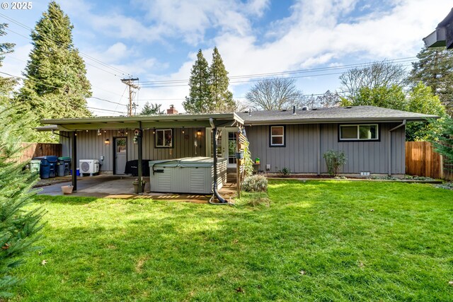 back of house with a hot tub, a yard, and a patio area