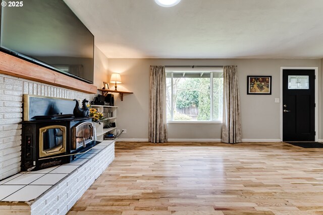 living area featuring light hardwood / wood-style floors, an AC wall unit, brick wall, and a wood stove