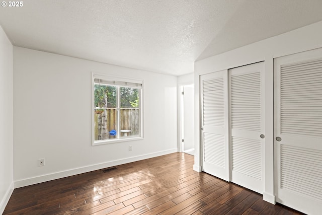 4844 SW Wembley Pl, Beaverton, OR 97005 - unfurnished bedroom featuring a textured ceiling, dark wood-type flooring, and multiple closets