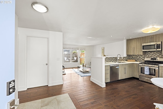 4844 SW Wembley Pl, Beaverton, OR 97005 - kitchen with stainless steel appliances, light countertops, dark wood-style flooring, a peninsula, and backsplash