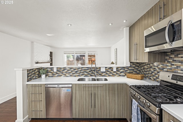 4844 SW Wembley Pl, Beaverton, OR 97005 - kitchen with appliances with stainless steel finishes, light countertops, decorative backsplash, dark wood-style flooring, and a peninsula