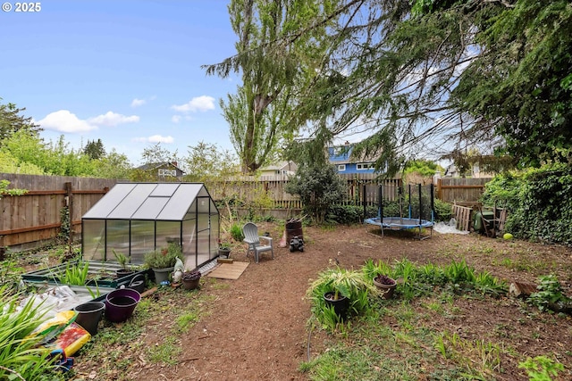 view of yard featuring a fenced backyard, a trampoline, an outbuilding, and an exterior structure