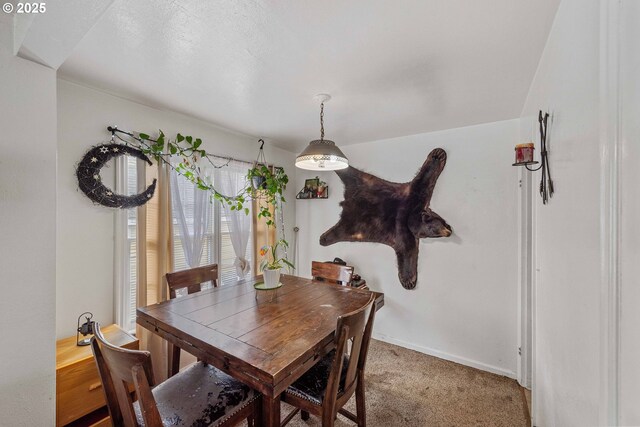 dining area with baseboards and light carpet