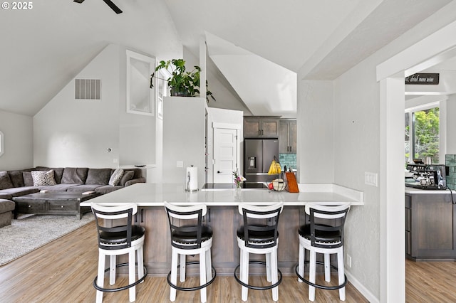 3430 Breezewood Ave, Eugene, OR 97405 - kitchen featuring light wood-style floors, stainless steel refrigerator with ice dispenser, lofted ceiling, a breakfast bar area, and light countertops
