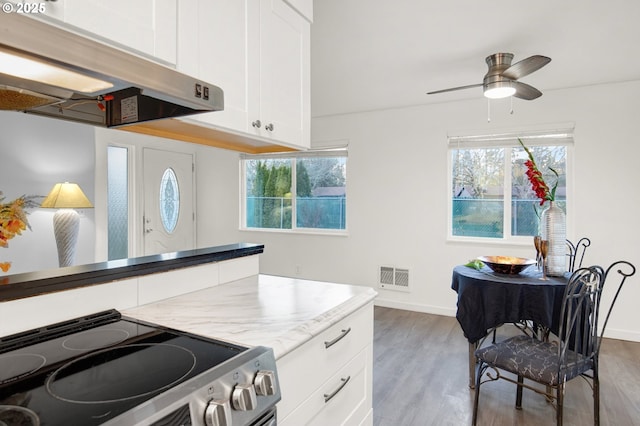 kitchen with white cabinetry, ceiling fan, dark hardwood / wood-style flooring, range hood, and stainless steel range with electric cooktop