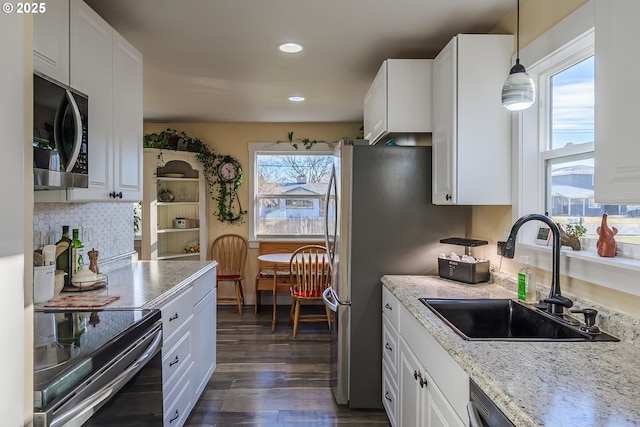 kitchen with hanging light fixtures, white cabinetry, sink, and electric range oven