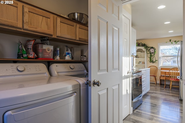 clothes washing area featuring cabinets, separate washer and dryer, and light hardwood / wood-style floors