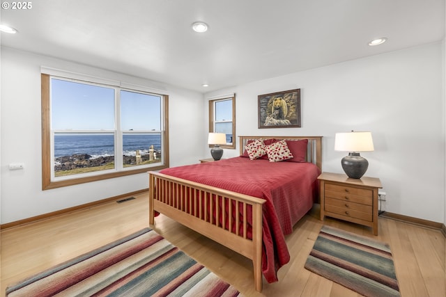 bedroom featuring light wood-type flooring and a water view