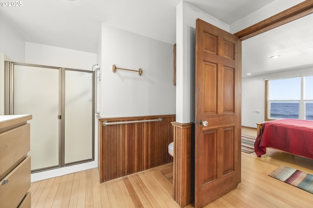 bathroom with a water view, toilet, an enclosed shower, and hardwood / wood-style flooring