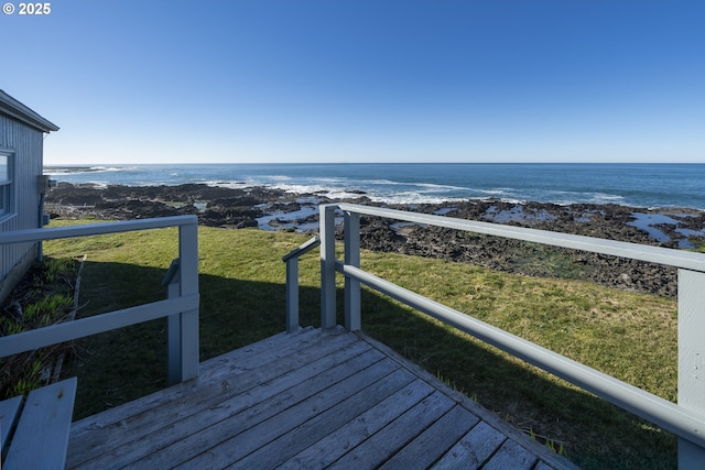 exterior space featuring a deck with water view and a beach view