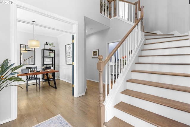 stairs with wood finished floors, ornamental molding, and baseboards