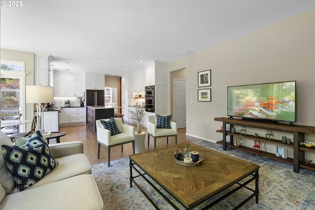 living area with light wood-style flooring, baseboards, and recessed lighting