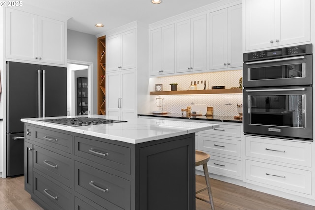 kitchen featuring gray cabinetry, high quality fridge, white cabinets, stainless steel gas cooktop, and tasteful backsplash