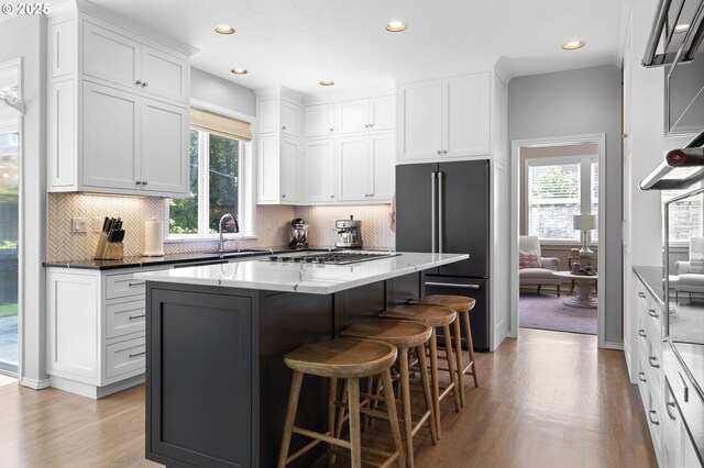 kitchen with high end fridge, a sink, light wood-style floors, white cabinetry, and healthy amount of natural light