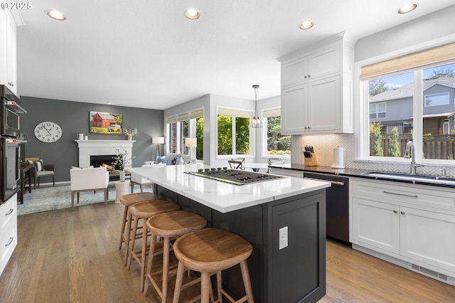 kitchen with healthy amount of natural light, open floor plan, a sink, white cabinets, and recessed lighting