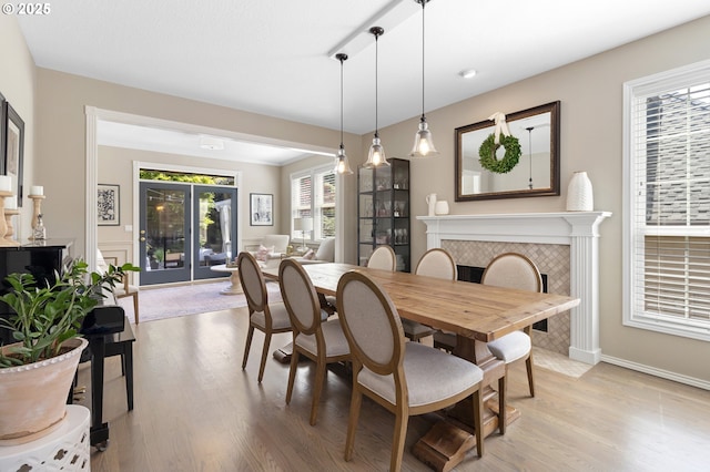 dining area featuring light wood-style flooring, a fireplace, and baseboards