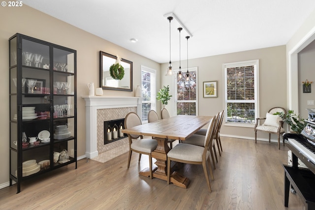 dining space featuring a tiled fireplace, wood finished floors, and baseboards