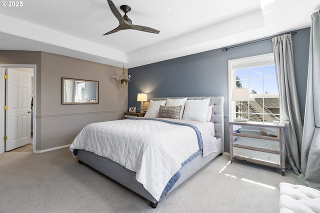 carpeted bedroom with a tray ceiling, baseboards, and ceiling fan
