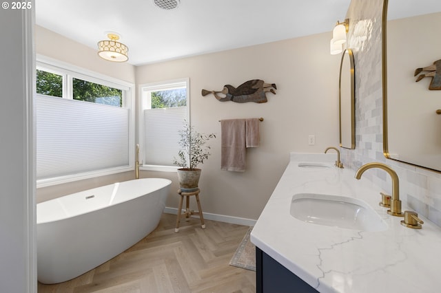 bathroom with a freestanding bath, double vanity, and baseboards