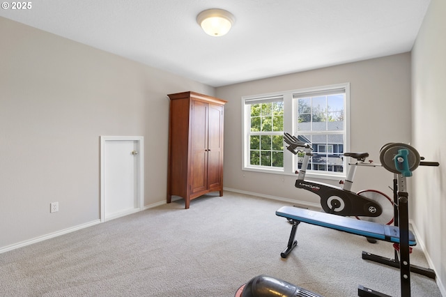 exercise area featuring light colored carpet and baseboards