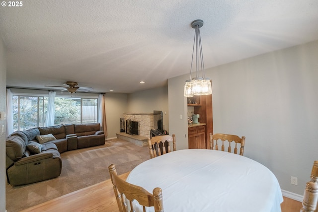 4635 18th Pl S, Salem, OR 97302 - dining space with a fireplace, light wood-style floors, ceiling fan, baseboards, and a textured ceiling