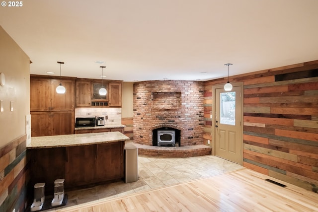 4635 18th Pl S, Salem, OR 97302 - kitchen with brown cabinets, a wood stove, black microwave, light stone countertops, and decorative backsplash