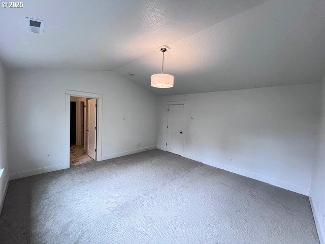 carpeted spare room with lofted ceiling and baseboards